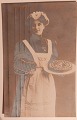 Postkort: 
"Glædeligt 
Nytår"" Kvinde 
med to kager. 
Én i hver sin 
arm. Annulleret 
AALBORG i 1910. 
...
