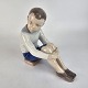 Figur af 
håndmalet 
porcelæn, 
udformet som en 
dreng siddende 
på en bog. Nr. 
1742
Producent ...