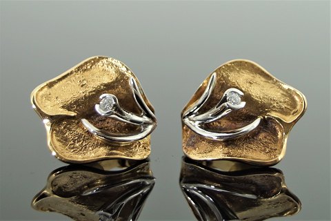 Ole Lynggaard; A pair of earclips of 14k gold and white gold with a diamond