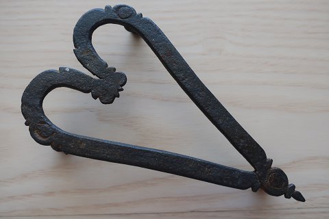 Antik håndsmedet strygejernsfod
Dette smukke stykke håndsmedede jern, - håndsmedet i form af et hjerte, er 
formentlig en oprindelig kærestegave
L: 15cm
B: 8,5cm
H: ca. 3cm
1800-tallet