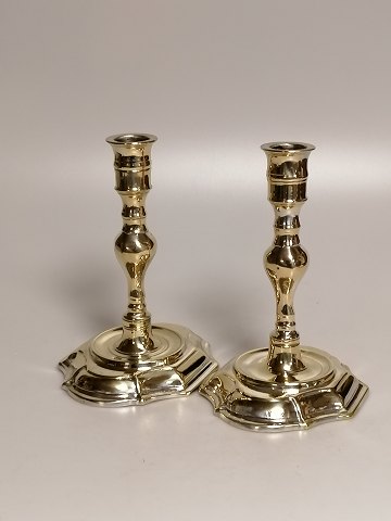 A pair of baroque brass candlesticks on an oval 
base. Stamped