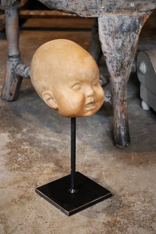 Buste af børne hoved i terracotta stående på jern fod , en del af figuren 
"Nina på kuglen" af Kai Nielsen. H:34cm.