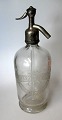 Chiffonflaske i 
glas, o. 1900. 
Med æstning: 
Bryggeriet 
Ceres. 
Mineralvandsfabrik.
 H.: 32 cm. ...