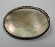 Brooch with 
mother of 
pearl. o. 1920. 
In silver 
mounts. Oval. L 
.: 5,5 cm.