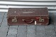 Brun kuffert 
med metalbeslag 
og funktionel 
lukning. 
Enkelte af 
kuffertens 
beslag er let 
rustne. ...
