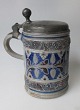 Tysk antik 
stentøjs krus 
med tin låg, 
1769. 
Saltglasur. 
Dekoreret med 
bladværk. Låg 
med gæk og ...
