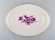 Antikt ovalt Meissen serveringsfad i håndmalet porcelæn med lilla blomster og 
guldkant. Ca. 1900.
