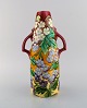 Stor antik art 
nouveau vase 
med hanke i 
glaseret 
keramik. 
Håndmalede 
blomster og 
bladværk på rød 
...