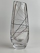 Svensk vase af 
klart glas med 
hvide, røde og 
sorte tråde 
samt skrå top. 
Vasen er 
designet af den 
...