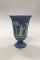 Wedgewood Blå 
vase på fod med 
dekoreret med 
offerkar og 
Amor. Måler 19 
cm(7 31/64 in.)