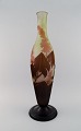 Kolossal antik Emile Gallé "Ricin" vase i matteret kunstglas med lysebrunt og 
sart pink overfang udskåret i form af blomster og bladværk. Sjælden model. 
Tidligt 1900-tallet.
