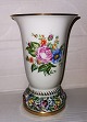 Trompet formet 
vase i porcelæn 
med fod hvorpå 
der er 
"blomsterbed" i 
relief. Bemalet 
øverst ! ...