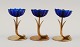 Gunnar Ander for Ystad Metall. Tre lysestager i messing og blåt kunstglas formet som blomster. ...