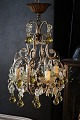 Dekorativ , gammel fransk lysekrone med klare glas prismer og glas kugler i en sart gul farve. ...