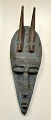 Afrikansk maske, midten af 1900-tallet. Udskåret træ med påbanket blå malet metal. Med to horn. ...