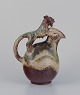 Bode Willumsen for Royal Copenhagen. Ceramic pitcher in sung glaze. Handle in 
the shape of a mythical creature.