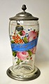 Tysk drikke 
krus, 1862. 
Glas dekoreret 
med 
emaljefarver i 
form af 
blomster og 
bånd, hvorpå 
der ...