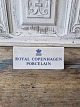 Royal 
Copenhagen 
Forhandlerskilt
Højde 6 cm. 
Længde 14 cm.