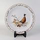 Flad 
middagstallerken 
i porcelæn med 
motiv af en 
fasan fra 
stellet 
Jagtstel.
Formgiver Mads 
...