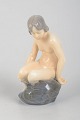 Adda Bonfils for Royal Copenhagen, pige på sten.Porcelænsfigur af en siddende pige på en ...