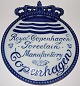 Kgl 
Porcelænsforhandler 
skilt. Måler 
23,2 cm. En 
Engelsk udgave. 
"Royal 
Copenhagen 
Porcelain ...