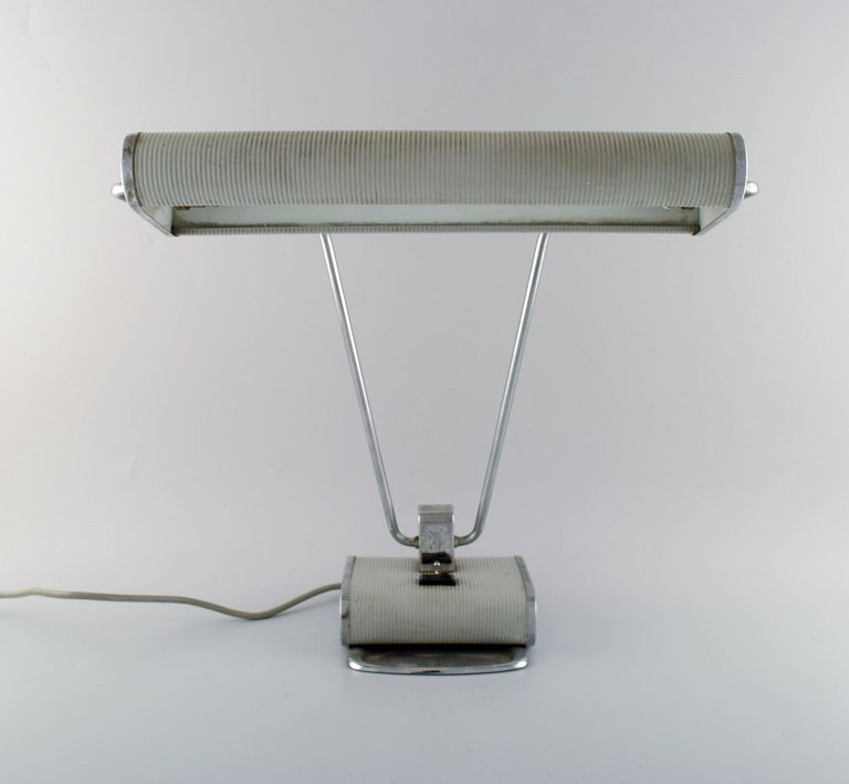 Eileen Gray 1878-1976. Skrivebordslampe af forkromet jern, grålakeret. Justerbar 
arm og skærm.