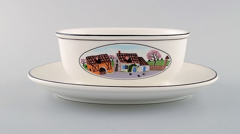 Villeroy & Boch Naif gravy boat on stand in porcelain decorated with naivist 
village motif.