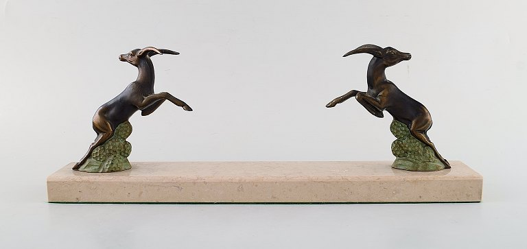 Art deco skulptur i form af springende bukke i patineret metal på marmorbase. 
1930